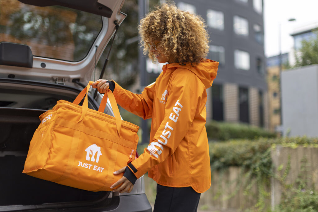 A Just Eat courier making a delivery with a delivery bag