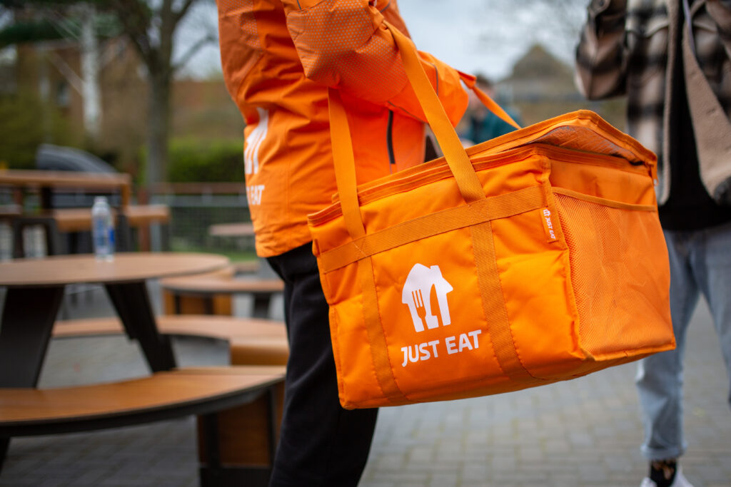 A Just Eat courier holding an orange delivery bag